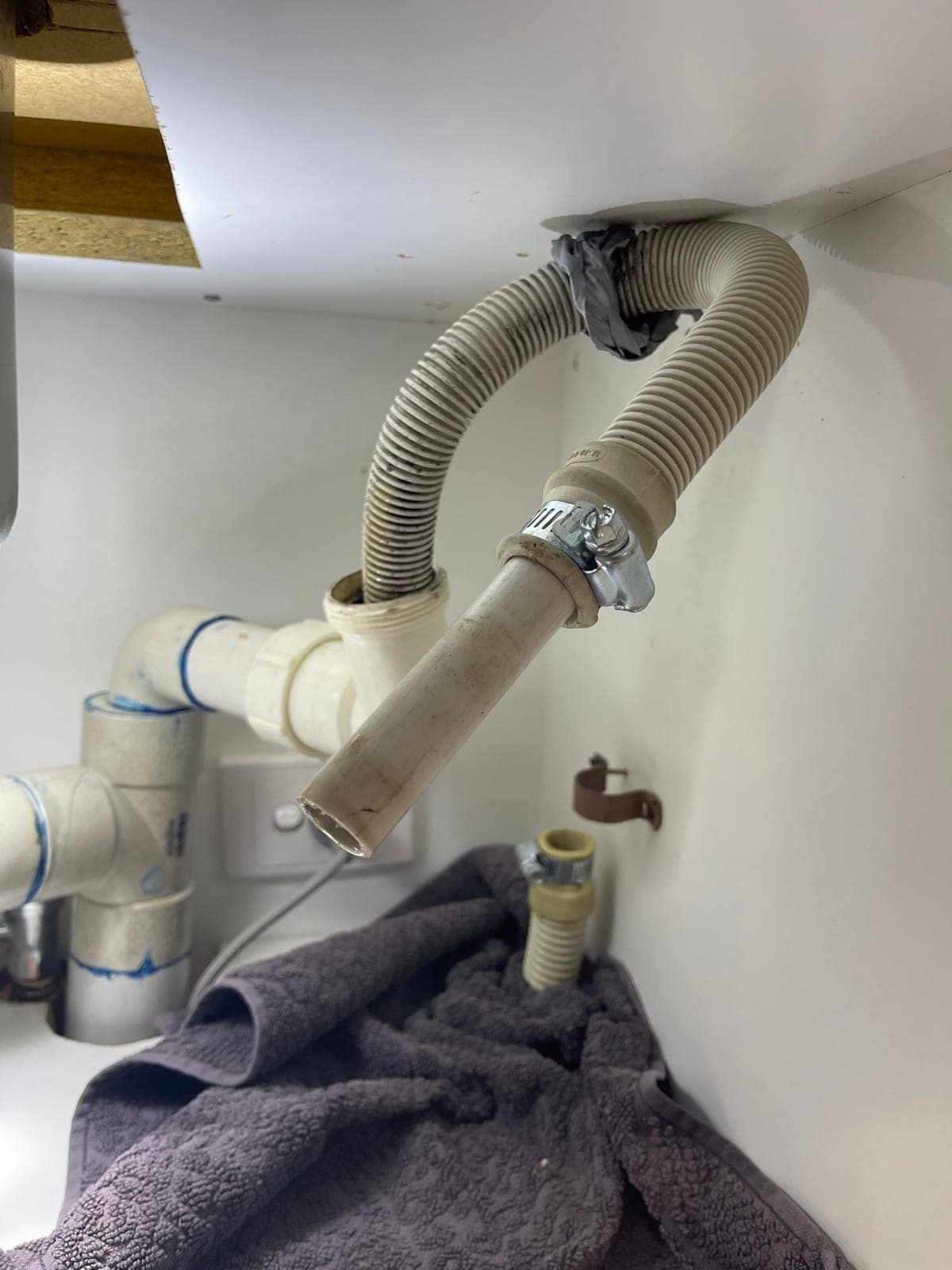 A dishwasher drain hose and its connection under the kitchen sink.