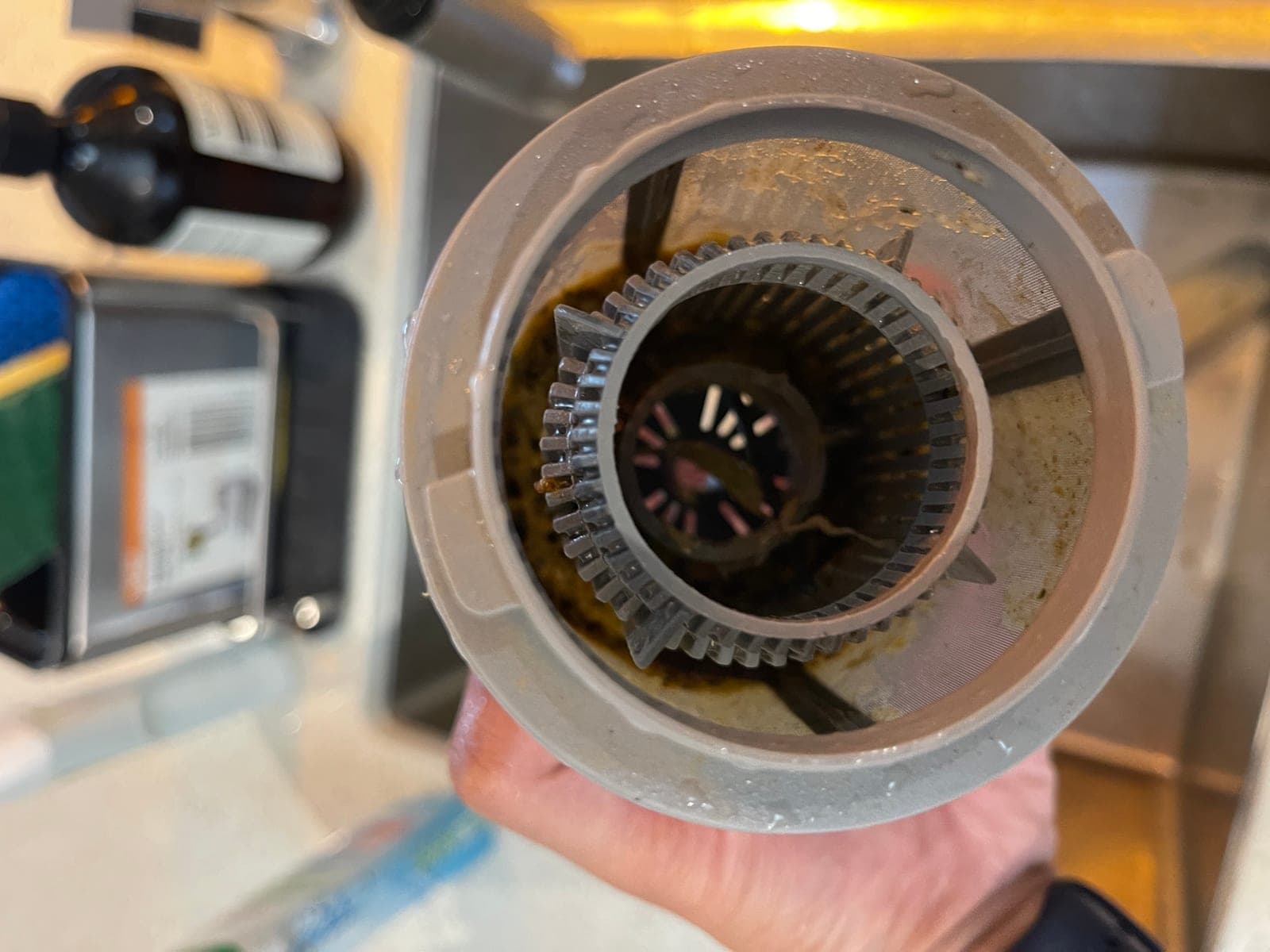A close view into a dishwasher filter cylinder packed with waste.