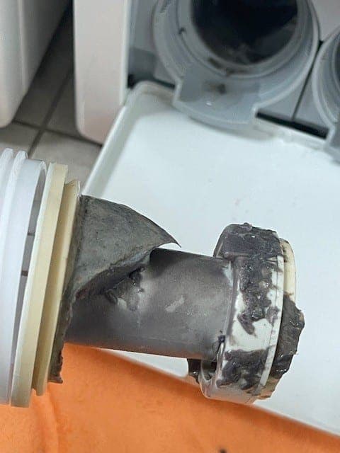 A dishwasher filter part-way through cleaning, with the debris visible.