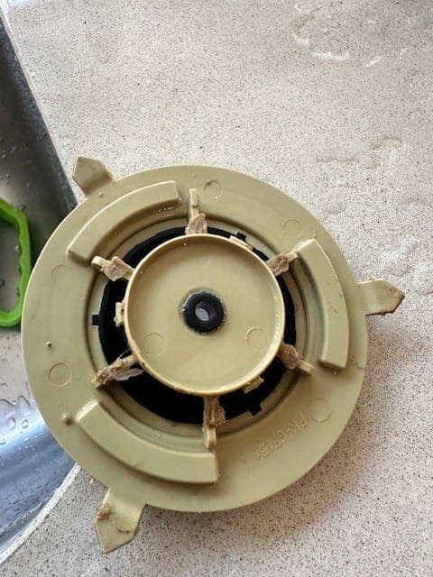 A dishwasher pump rotor removed and laid out, with fibrous debris wound between the vanes.