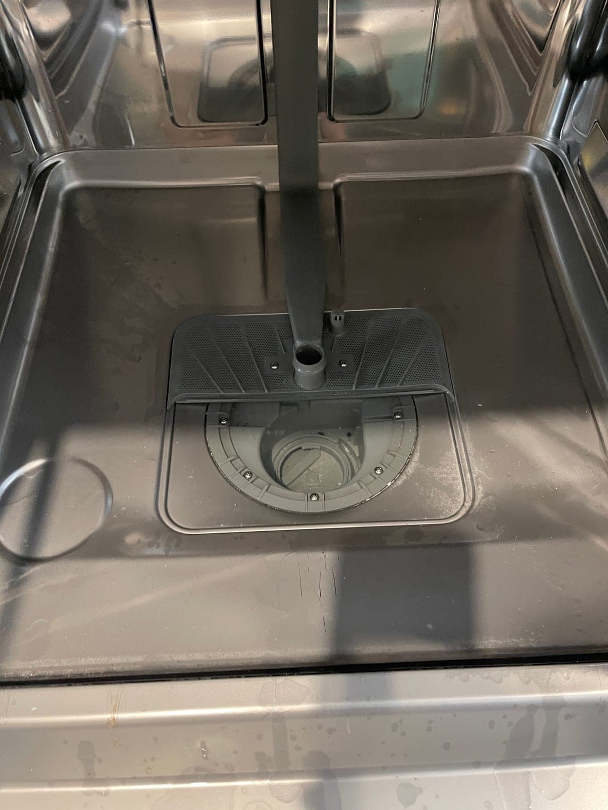 The lower spray arm and its mounting point inside a dishwasher.