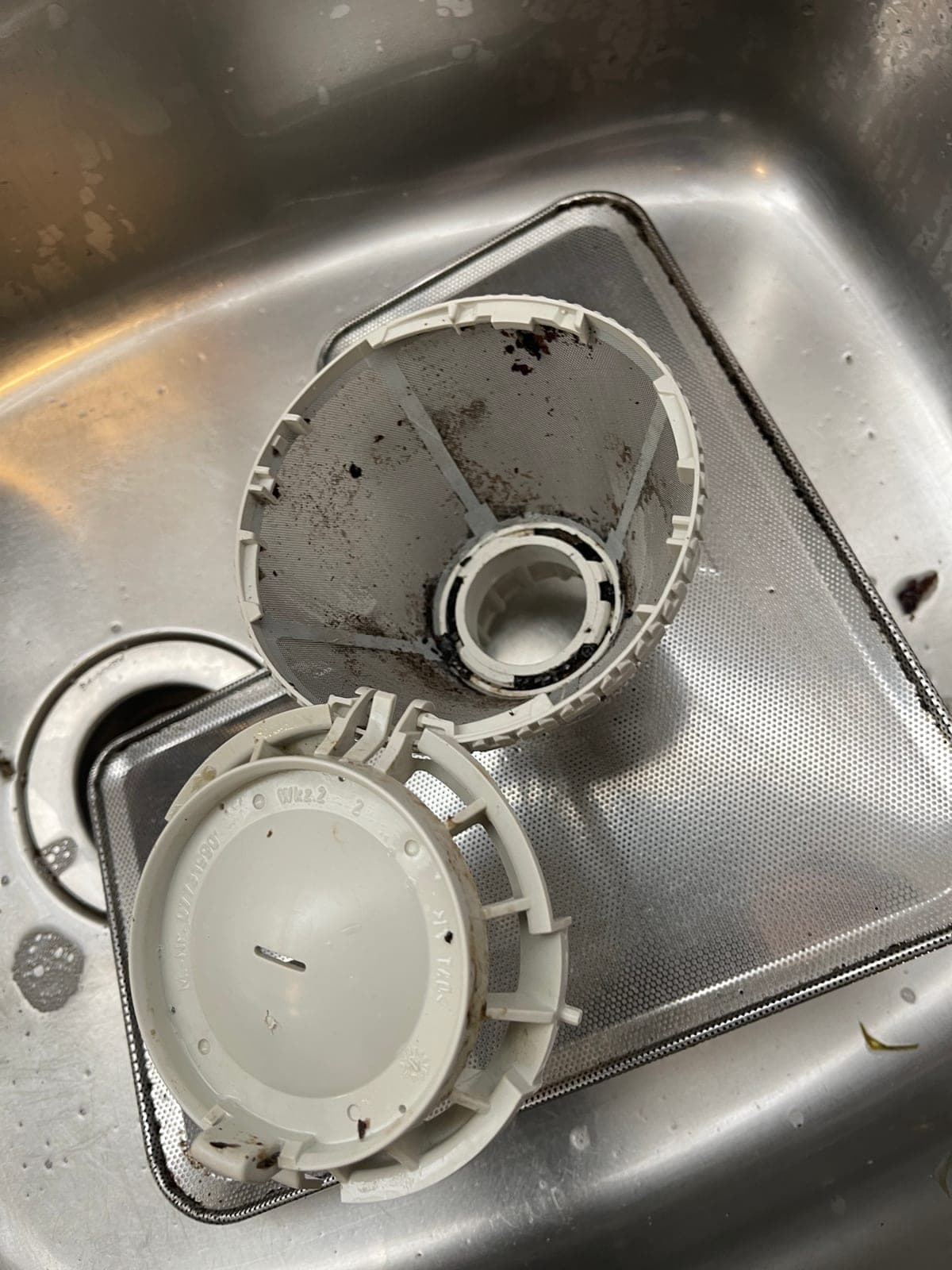 Debris caught in the sump housing at the base of a dishwasher tub.