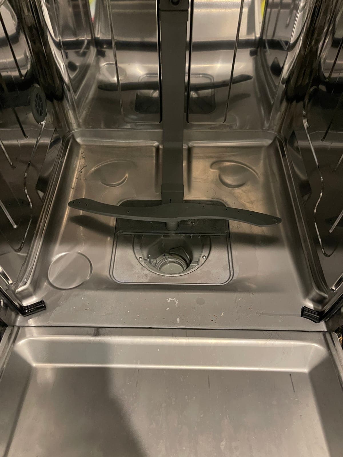 A dishwasher tub after a service, with the lower spray arm refitted.