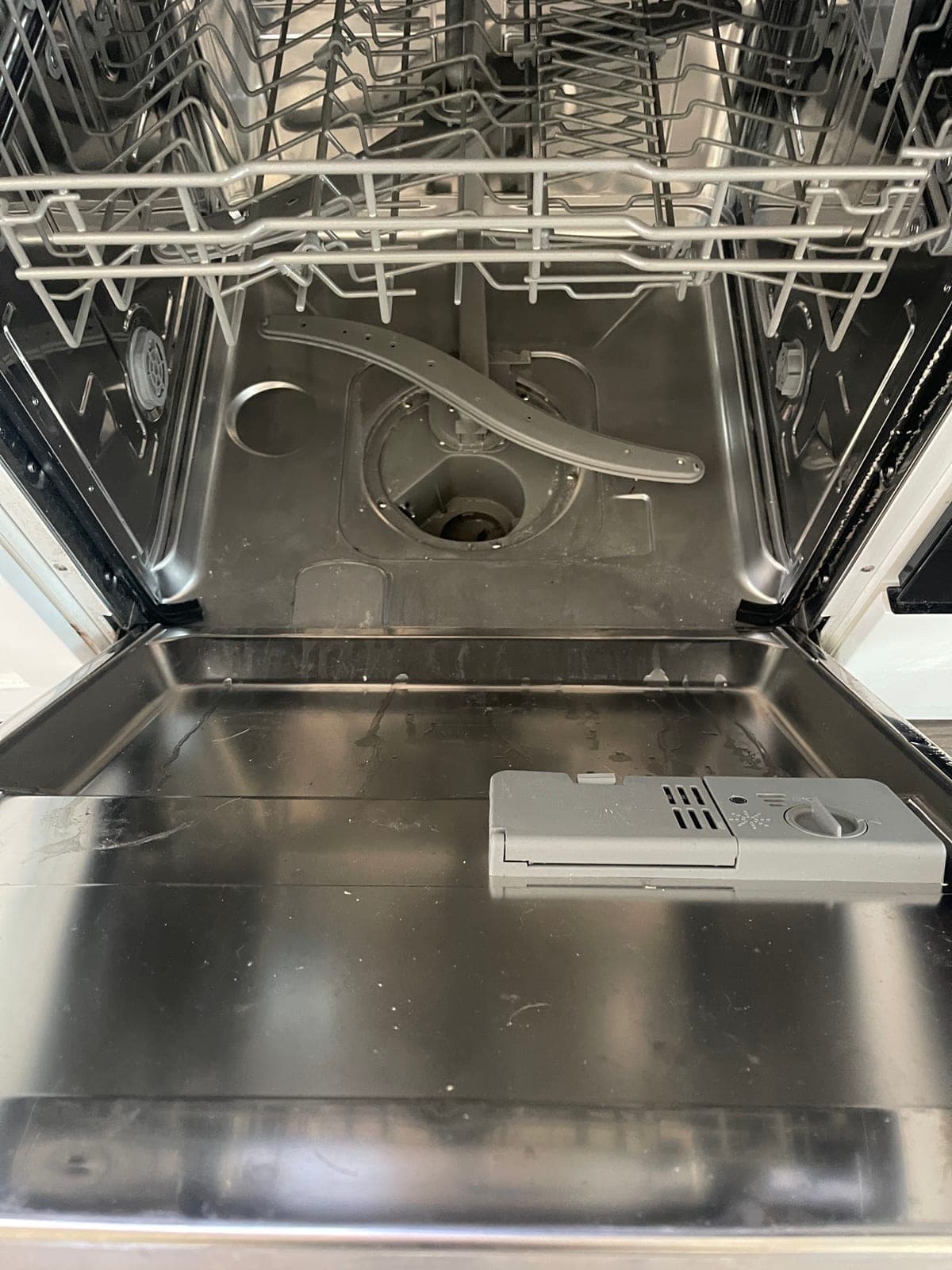 A dishwasher with the door open and racks out, ready for inspection.