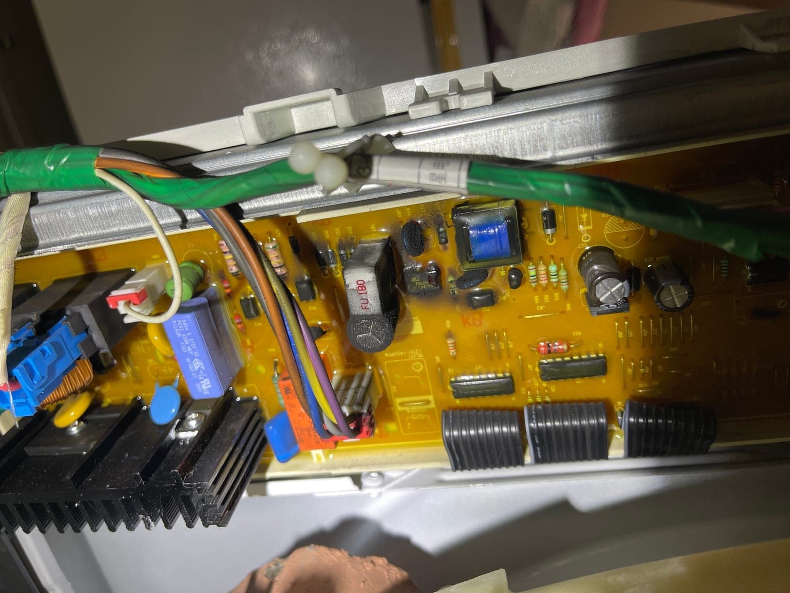 A washing machine control board with visible burn damage at the relay.
