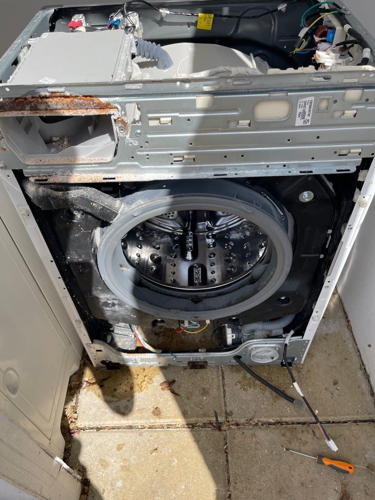 A washing machine cabinet stripped back to the drum and suspension.