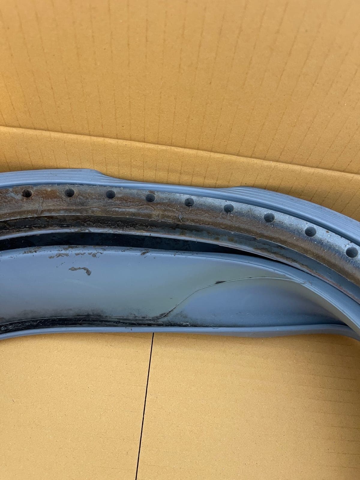 A perished washing machine door seal with the inner face worn through.
