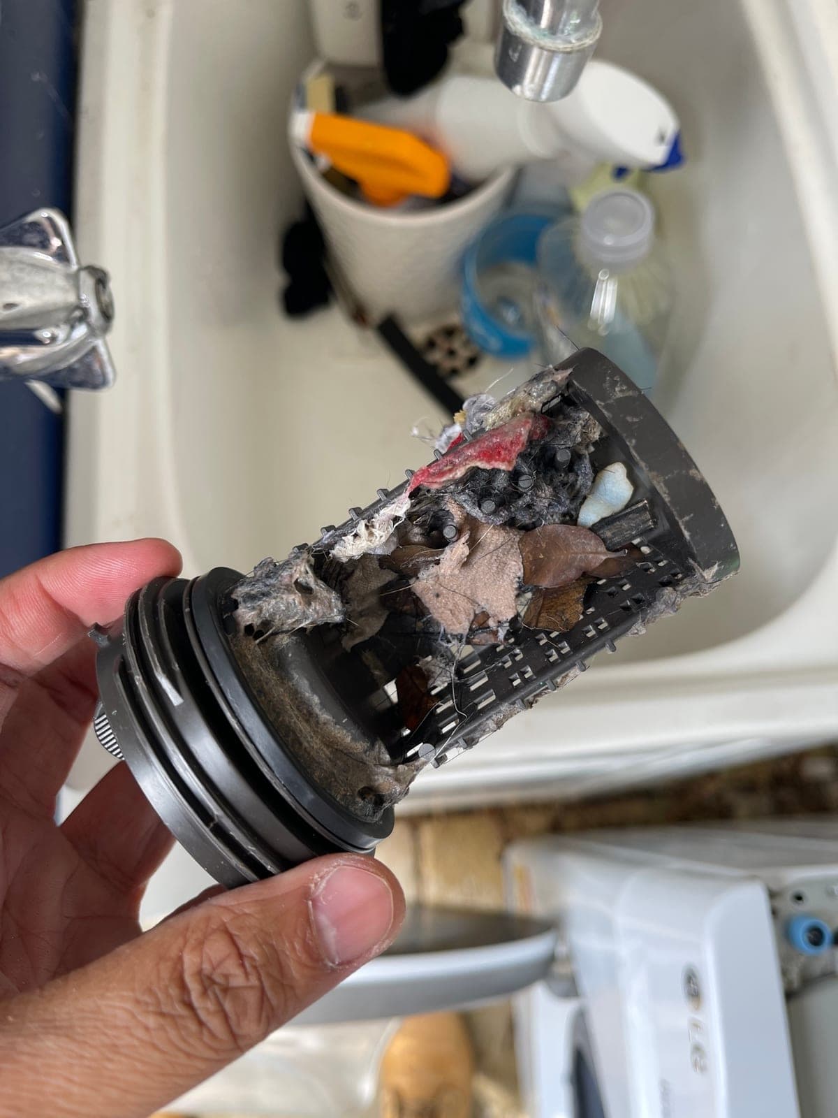A washing machine pump filter removed, packed with lint and hair.